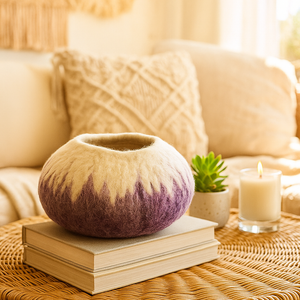 Decorative wool bowl on books with a candle and plant on a wicker table