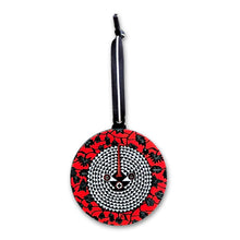 Round red and black patterned keychain with a white background