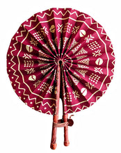 A traditional folding hand fan with a deep magenta-red fabric canopy featuring intricate white geometric and tribal patterns, complete with a brown wooden handle and leather strap, isolated on a white background.