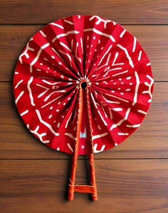 Red and white patterned fan with wooden handle on a white background