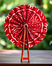 Red and white patterned fan with wooden handle on a white background