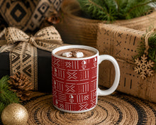 red white holiday coffee mug with an abstract cowrie shell pattern. the mug is filled with hot chocolate and surrounded by wrapped gifts.