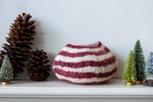 Striped red white vase on a shelf with decorative trees and pinecones