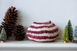 Striped red white vase on a shelf with decorative trees and pinecones