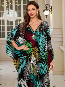 Woman wearing a colorful leaf-patterned dress indoors.