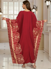 Woman wearing a red dress with gold pattern in an elegant interior setting