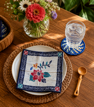 Decorative table setting with a floral napkin, glass of water, and wooden spoon on a wooden table.