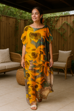 Woman wearing a orange floral kaftan  dress standing in an outdoor setting.