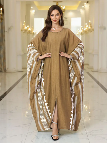 Woman wearing a brown tan dress with patterned sleeves in an elegant interior setting