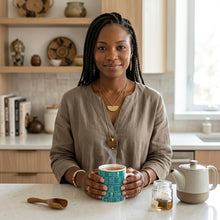 African American woman drinking a cup of tea in a teal blue African pattern coffee mug.