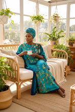 Turquoise dress with floral design on hangers against a white background
