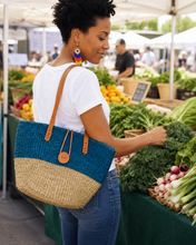Woman shopping at an outdoor farmers market with a two-toned African bag.