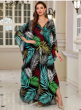 Woman wearing a colorful leaf-patterned dress in an elegant interior setting