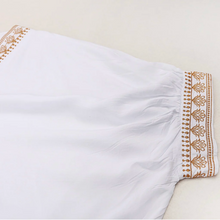 White dress with gold embroidery on a beige background