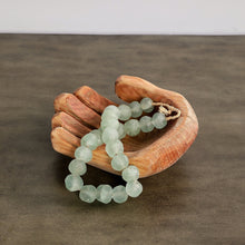 Green beaded bracelet on a wooden hand sculpture