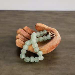 Green beaded bracelet on a wooden hand sculpture