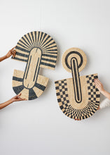 Woven baskets with geometric patterns held by hands against a white background