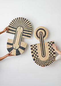 Woven baskets with geometric patterns held by hands against a white background