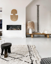 Modern living room with a fireplace, decorative african art, and a white rug.