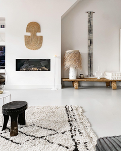 Modern living room with a fireplace, decorative african art, and a white rug.