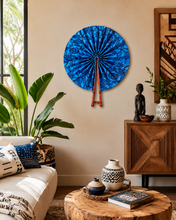 Living room with a blue decorative wall piece, wooden cabinet, and plants.