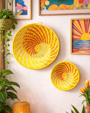 Yellow woven baskets on a wall with colorful artwork and plants in a room.