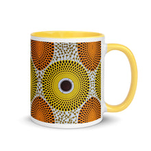 A ceramic coffee mug with a vibrant orange and yellow African pattern design.