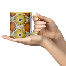 woman holding a yellow and orange african pattern coffee mug