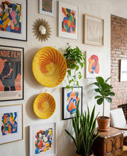 Wall with decorative items including framed art, a yellow woven basket, and plants.